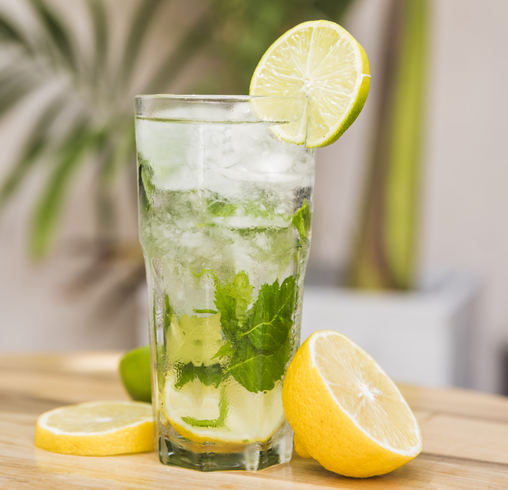 slices-fruits-near-glass-drink-with-ice-herbs-table