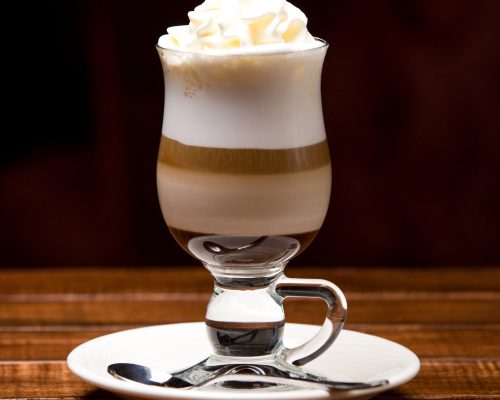 cup of hot latte with froth and cream